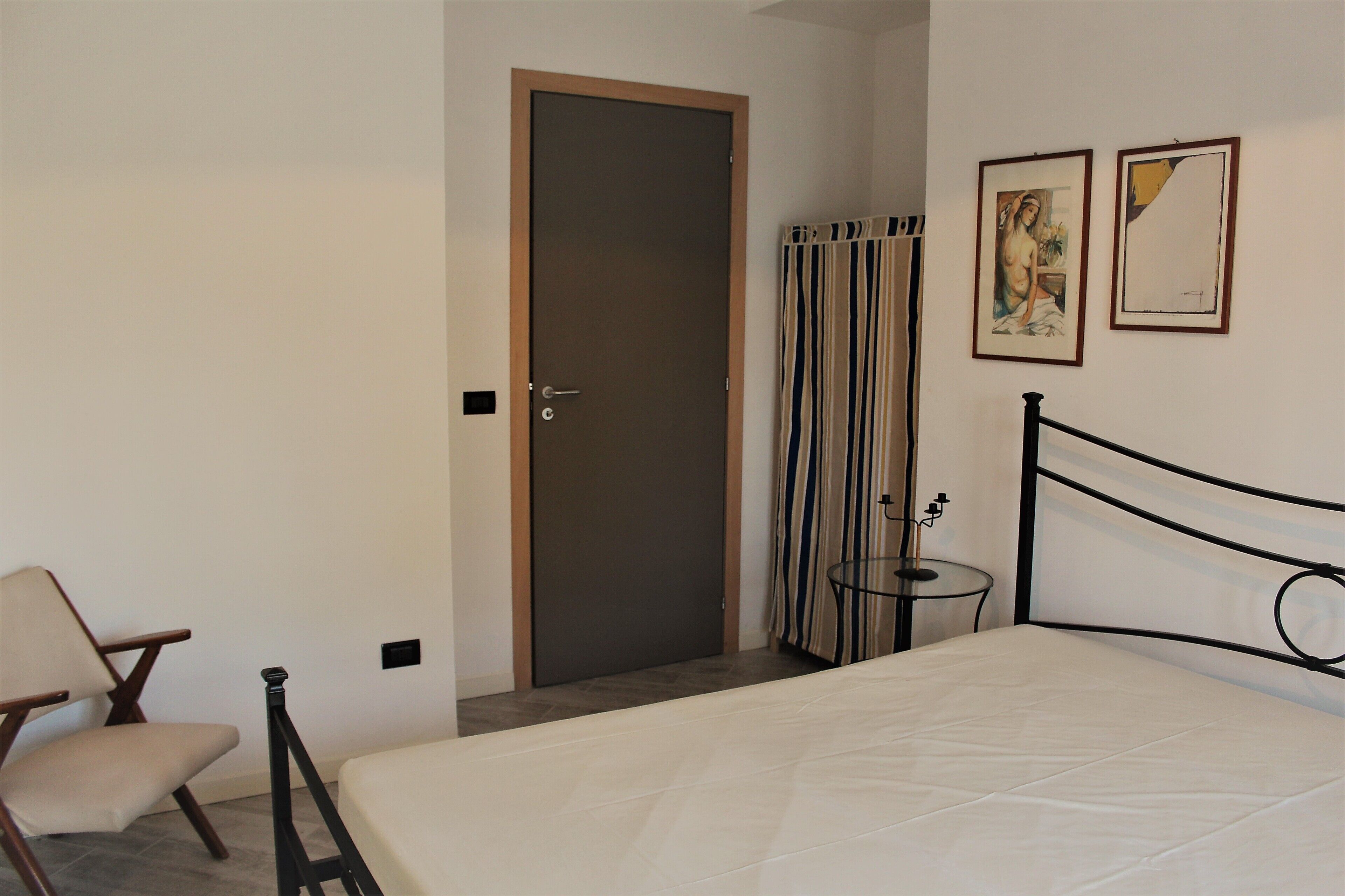 Une chambre à coucher avec un lit, une chaise, une porte et deux tableaux encadrés accrochés au mur.