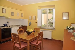 A compact kitchen with a dining table, chairs, and a bowl of fruit.