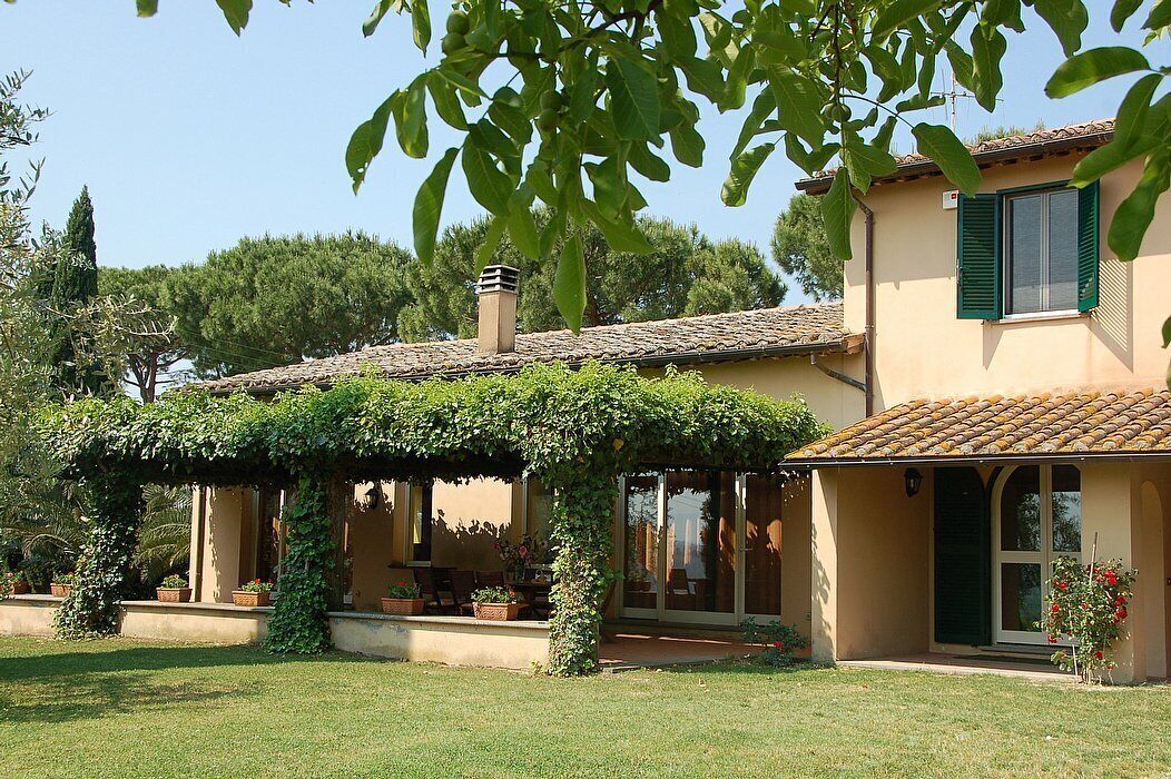 Una casa con portico coperto, un camino e un giardino con piante in vaso.