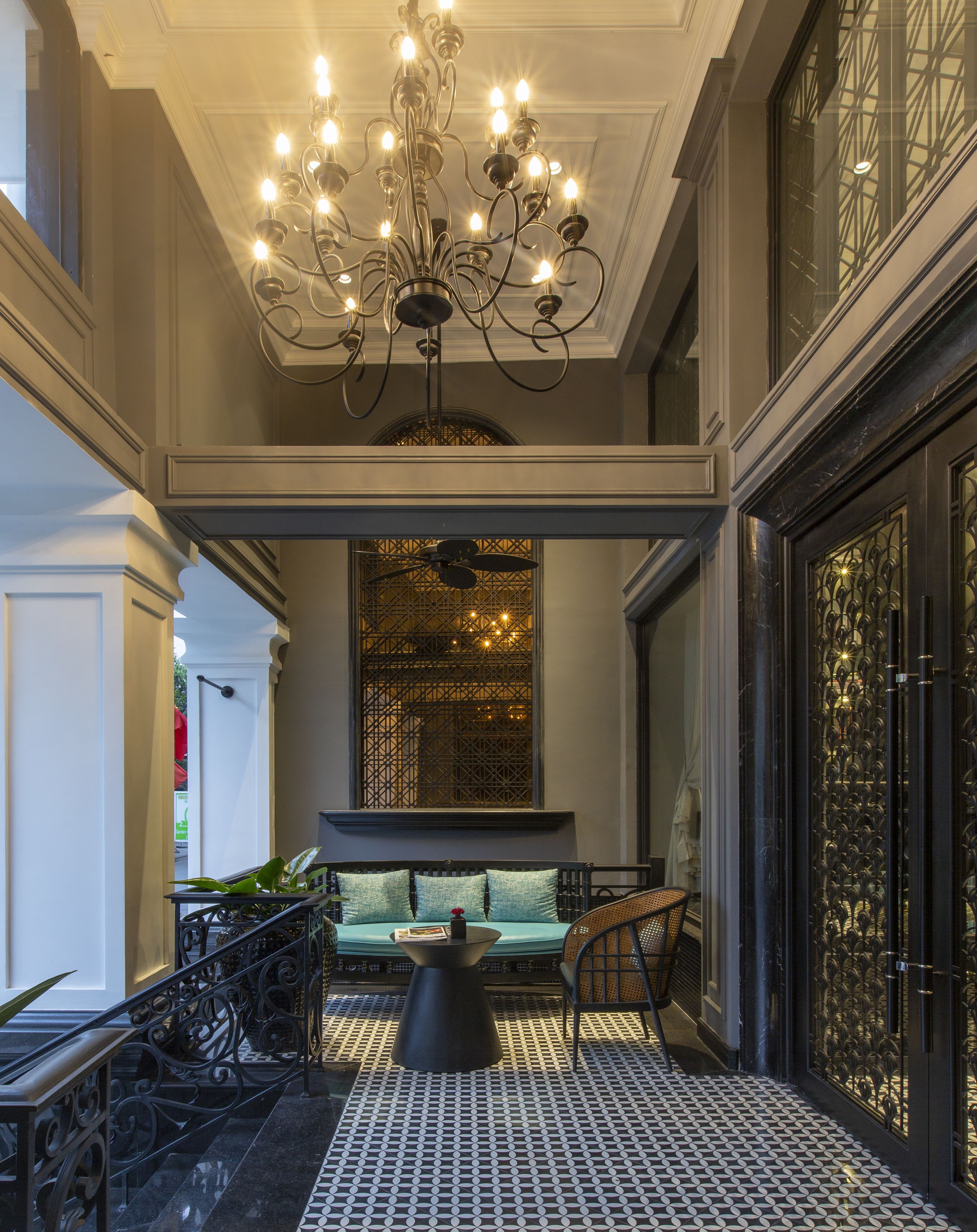 A grand lobby with a chandelier, a seating area with a table, and a patterned floor.