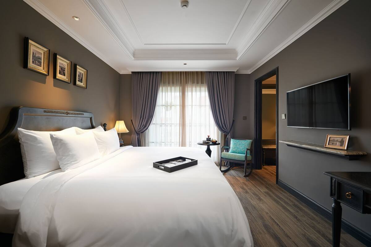 A hotel room with a large bed, a television, a small table, and a chair.