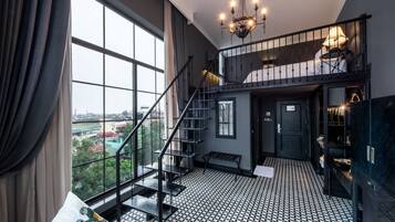 A spacious room with a large window, a staircase, and a chandelier.