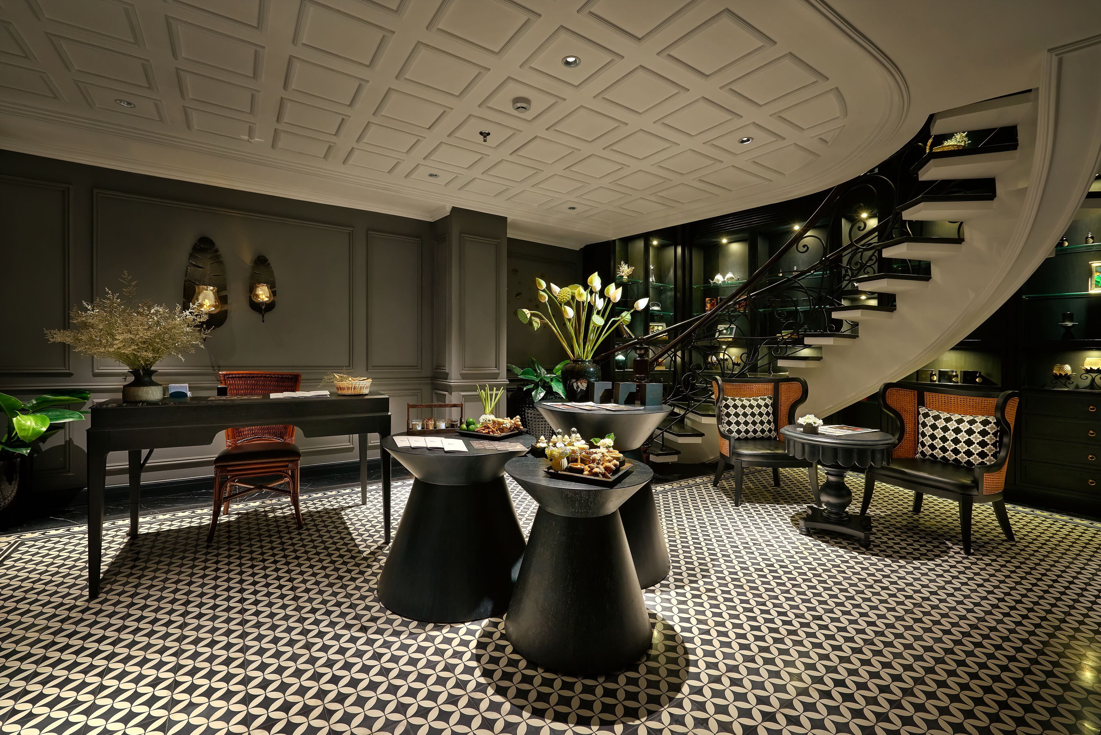A modern lobby with a geometric patterned floor, a curved staircase, and contemporary furniture.