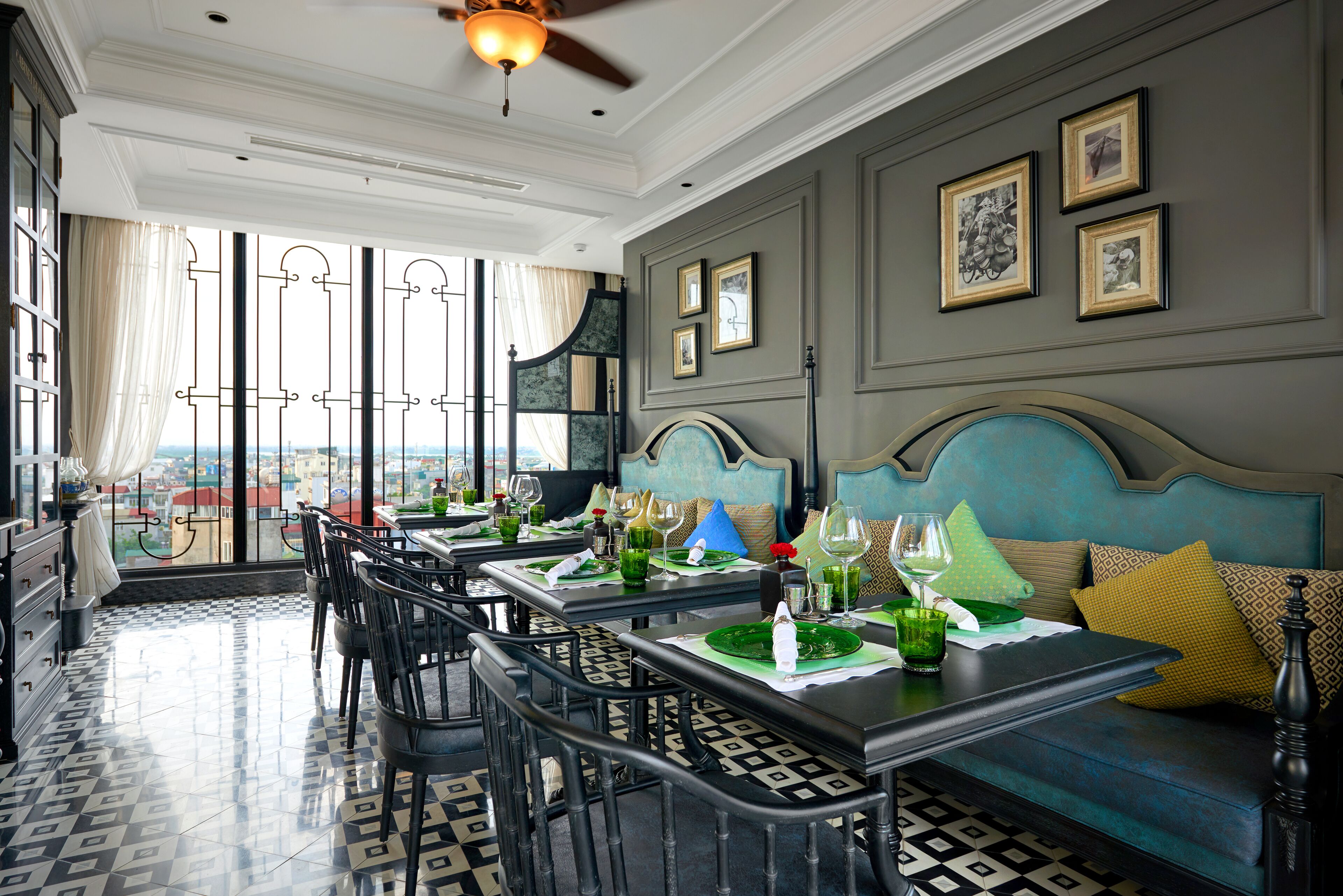 A dining area with tables set for a meal, a sofa with cushions, and framed pictures on the wall.