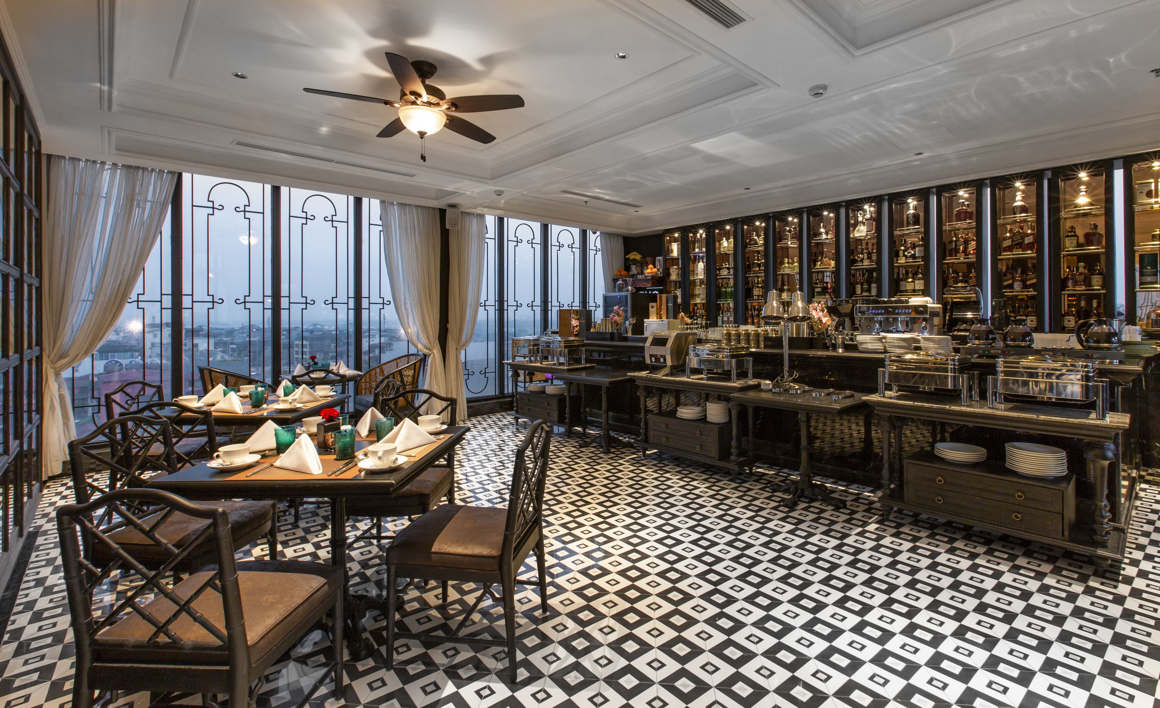 A dining area with a view of the city, a bar with various bottles, and a patterned floor.
