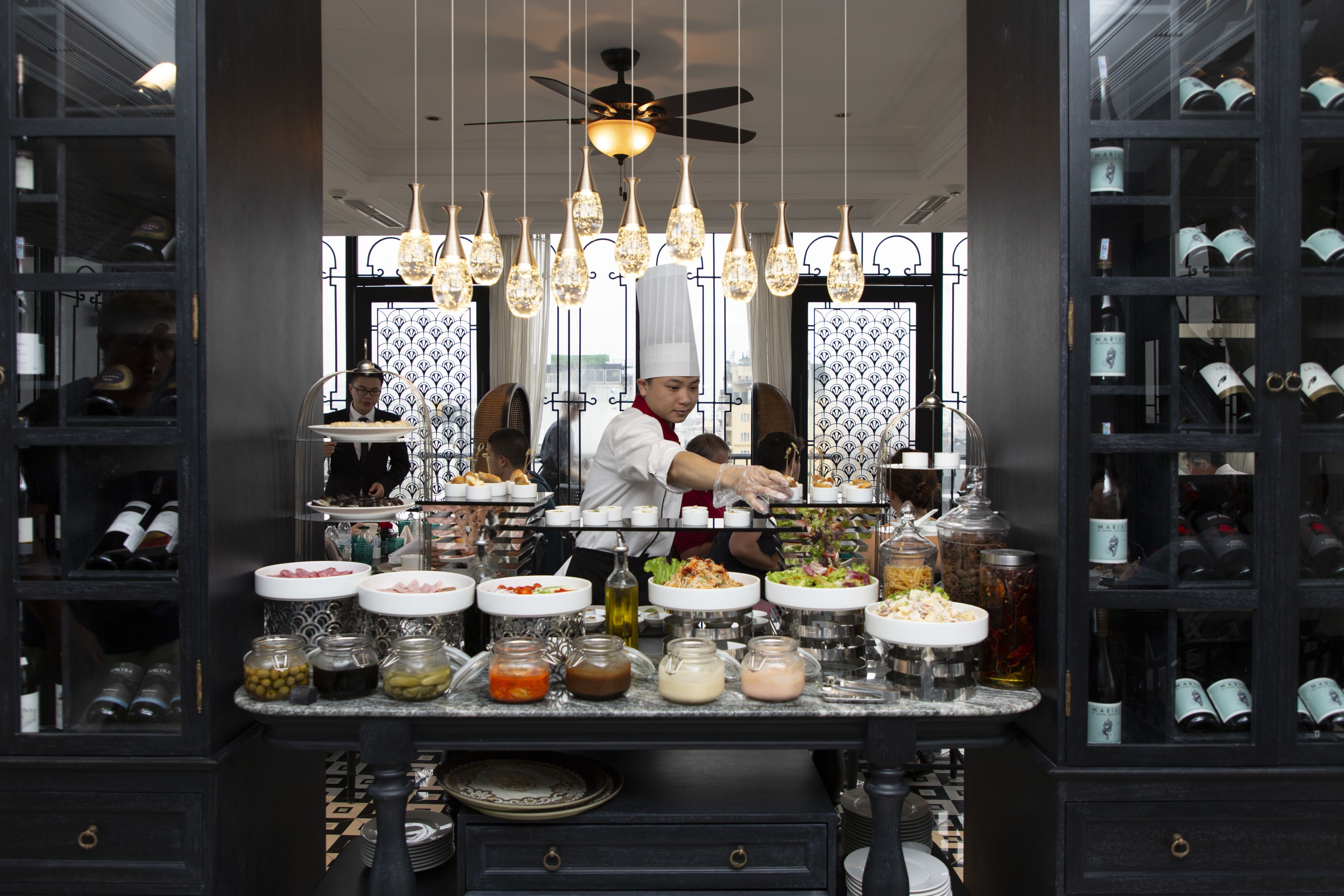 A chef preparing food in a modern kitchen with a wine rack and various food containers.