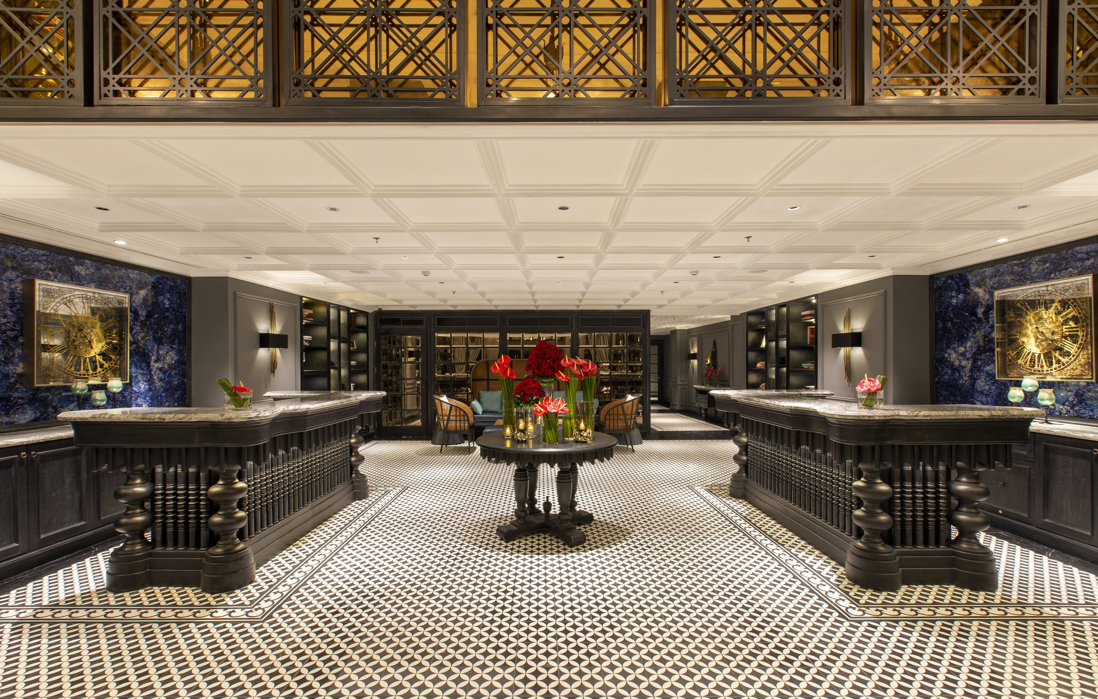 A luxurious lobby with a central round table, ornate railings, and a patterned floor.