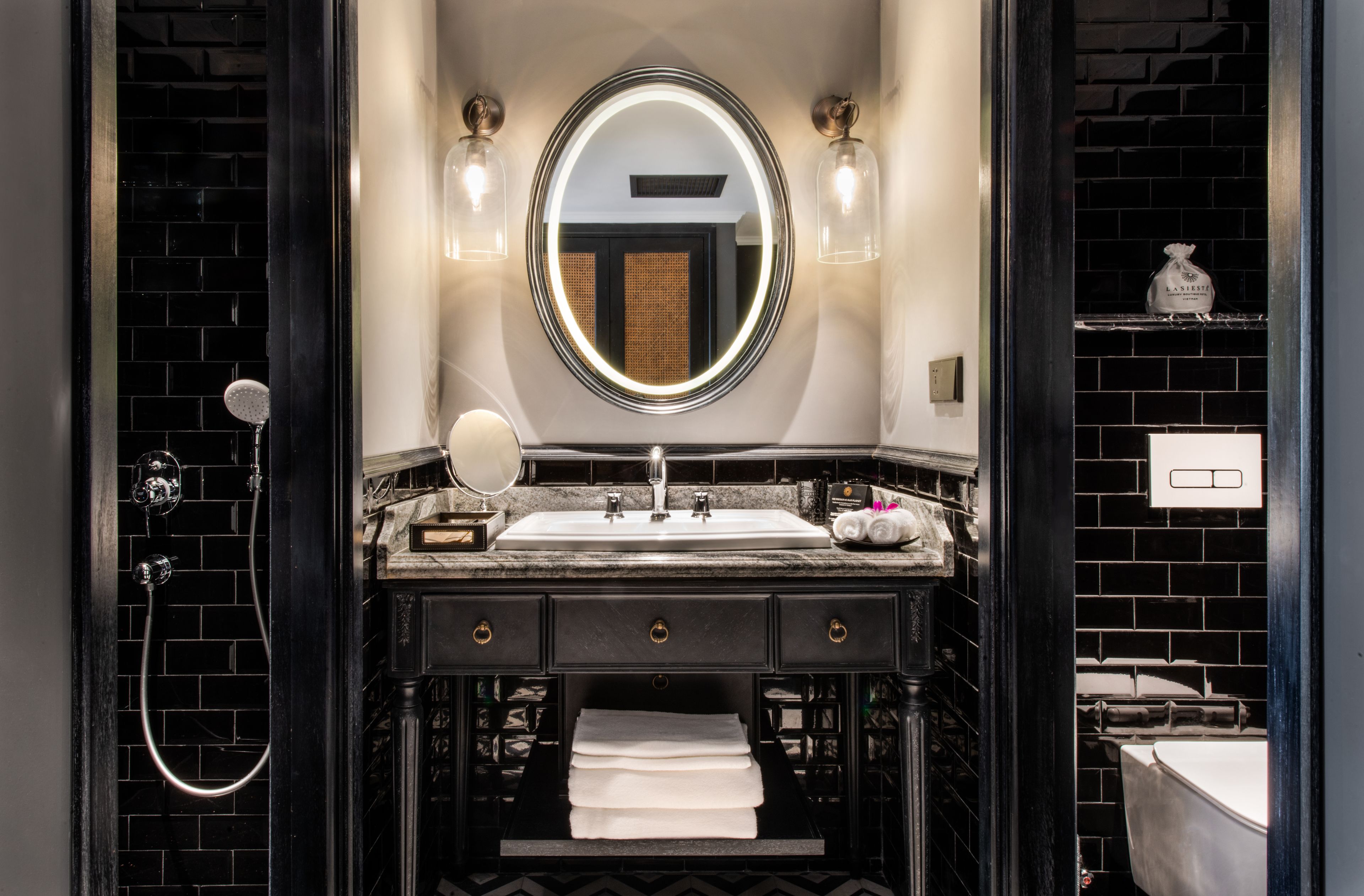 A modern bathroom with a black and white color scheme, featuring a large mirror, a sink, and a shower.