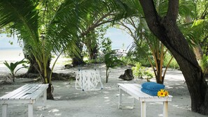 A beachside relaxation area with white benches and a table with towels and sunflowers. - La Due Thulusdhoo (Thulusdhoo Island)