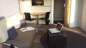 A hotel room with a sofa, a small table with a laptop, a chair, and a window. - SUPERB 2 ROOMS - PARIS LA DEFENSE- RESIDENCE 4* (Courbevoie)