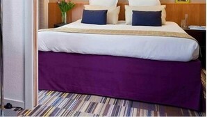 Habitación de hotel con cama, dos lámparas de pared, una mesita de noche y un cuadro enmarcado.