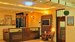 A reception area with a wooden counter, a chandelier, framed artwork, and a door labeled "Store Room." - Hotel Shivam Fort View (Chittorgarh)