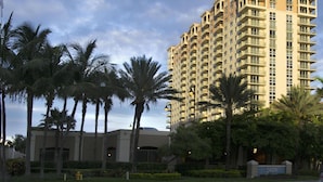 Un hotel moderno de gran altura con varios balcones, rodeado de palmeras y vegetación.