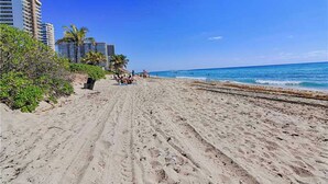 Una playa arenosa con palmeras y un cielo azul despejado.