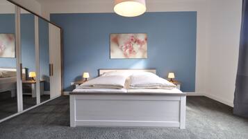 Un dormitorio con cama, lámparas de noche, un espejo grande y una obra de arte en la pared.