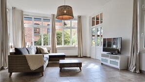 Ein Wohnzimmer mit Sofa, Hocker und TV-Schrank.