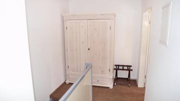 A hallway with a white wardrobe, a small table, and a door.