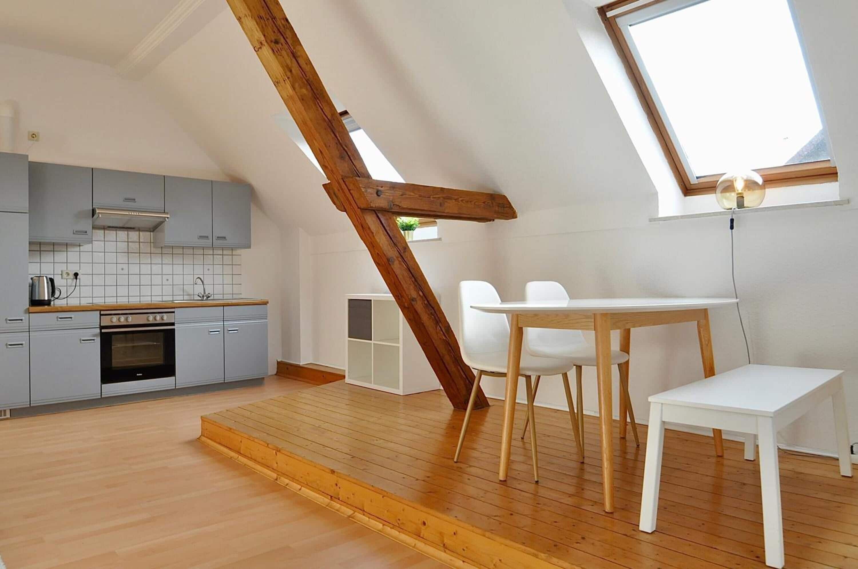 Una cocina moderna con armarios grises, una escalera de madera y un tragaluz.