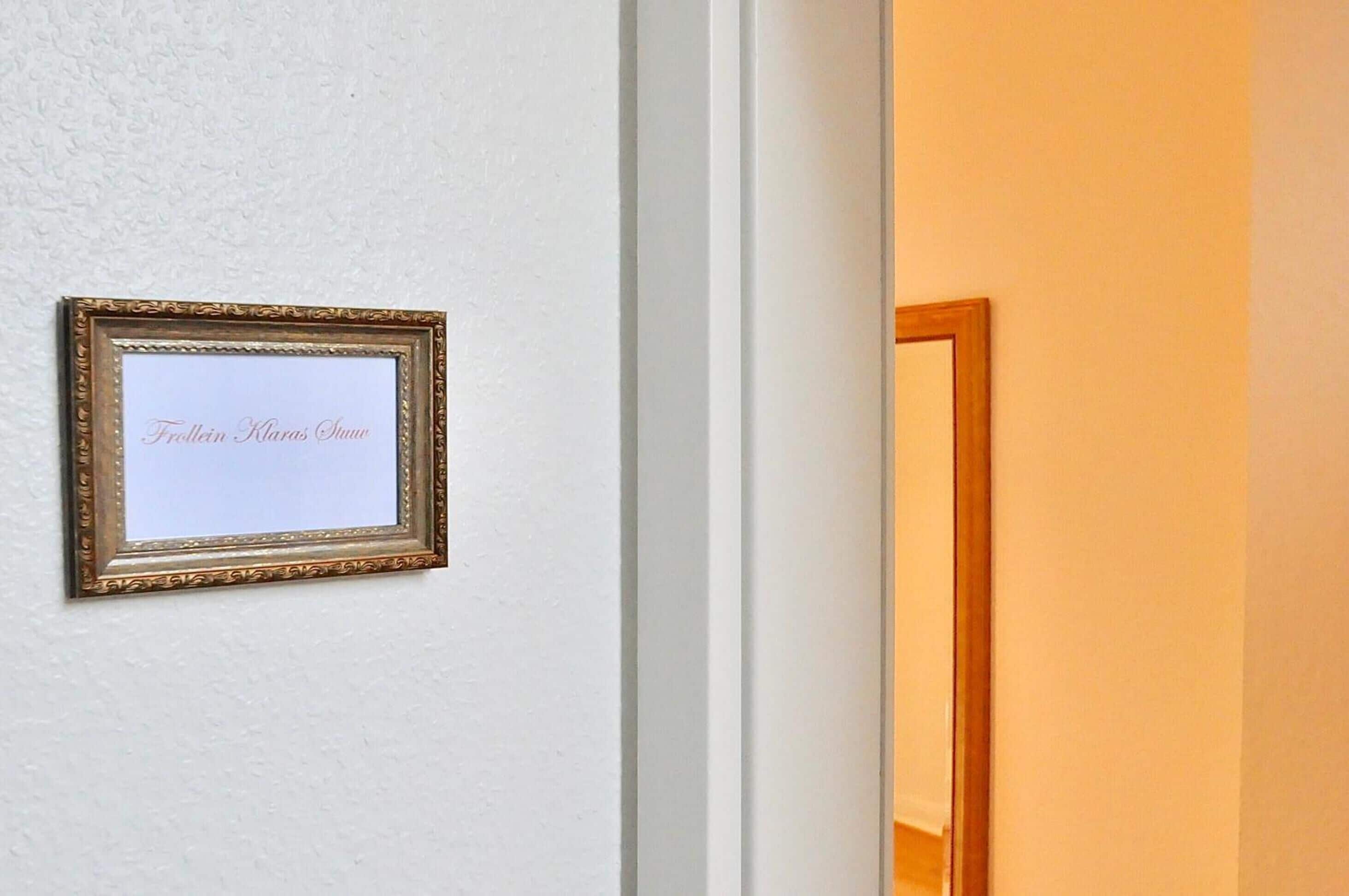 A framed sign with text on a white wall.