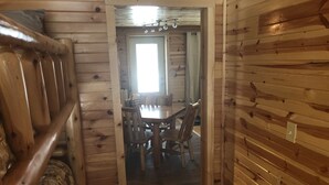 Een houten interieur met een eethoek, een raam en een deur naar een andere kamer.