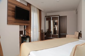 Quarto de hotel com cama grande, televisão na parede, guarda-roupa e espelho.