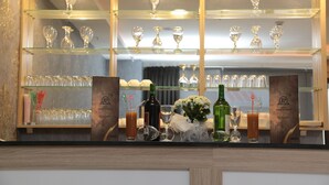 A bar area with multiple shelves of wine glasses and bottles, a menu stand, and a decorative vase with flowers. - Paris Prestige (Izmir)