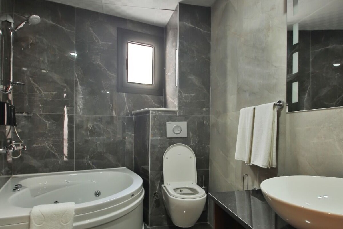 A modern bathroom with a bathtub, toilet, and sink.
