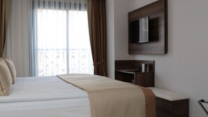 A modern hotel room with a large bed, a flat-screen TV mounted on the wall, and a small desk area. - Paris Prestige (Izmir)