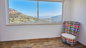 A room with a large window offering a view of a mountainous landscape.