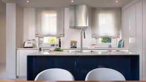Una cocina moderna con una isla central, electrodomésticos de acero inoxidable y una zona de comedor con dos sillas.