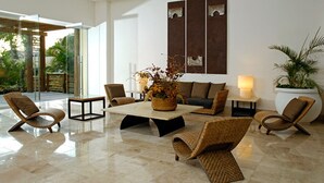 Eine geräumige Lobby mit einem zentralen Couchtisch, umgeben von Korbstühlen, einer Couch und einer Topfpflanze.