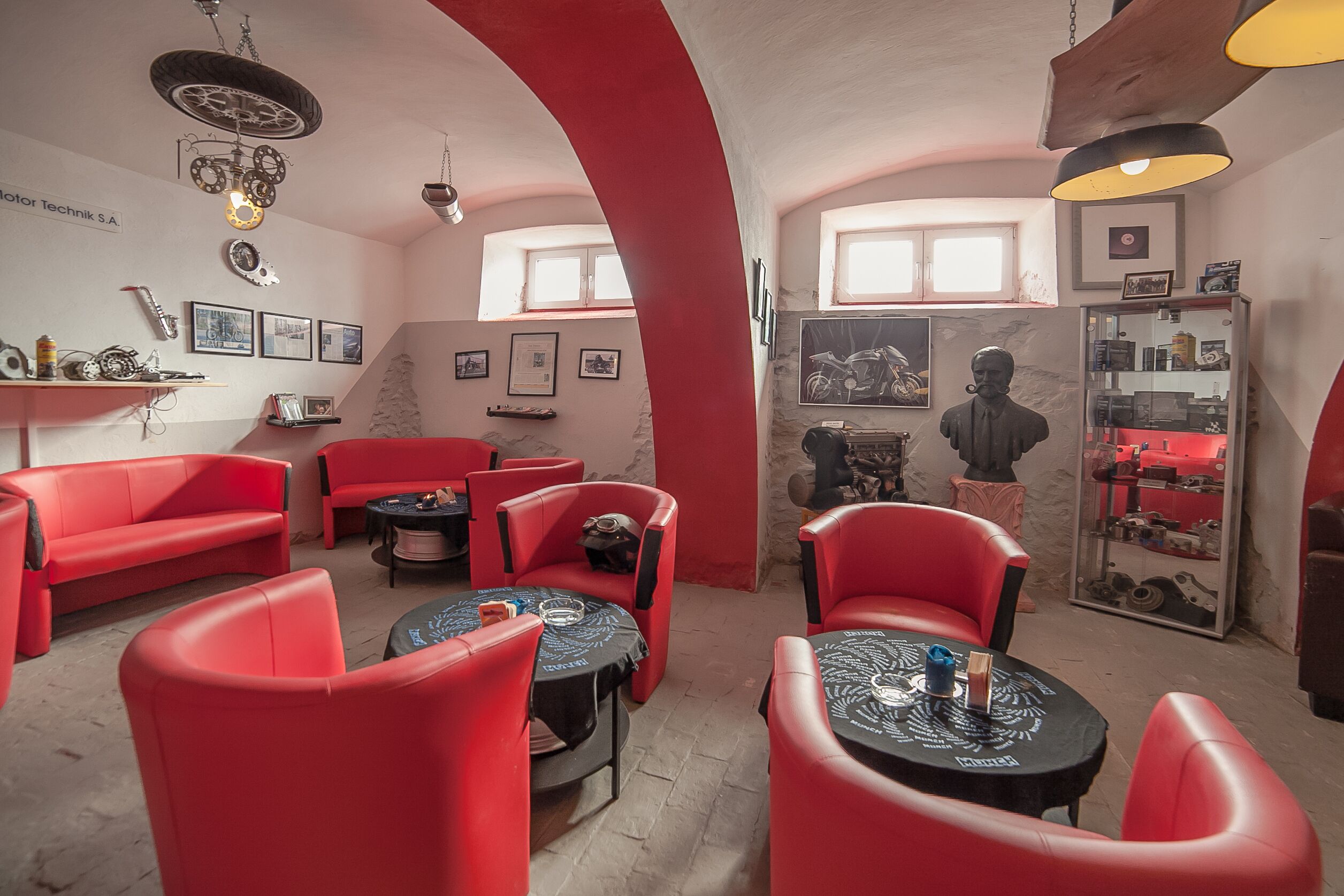 Una habitación con muebles rojos, una estatua de motocicleta y un estante montado en la pared con varios objetos.
