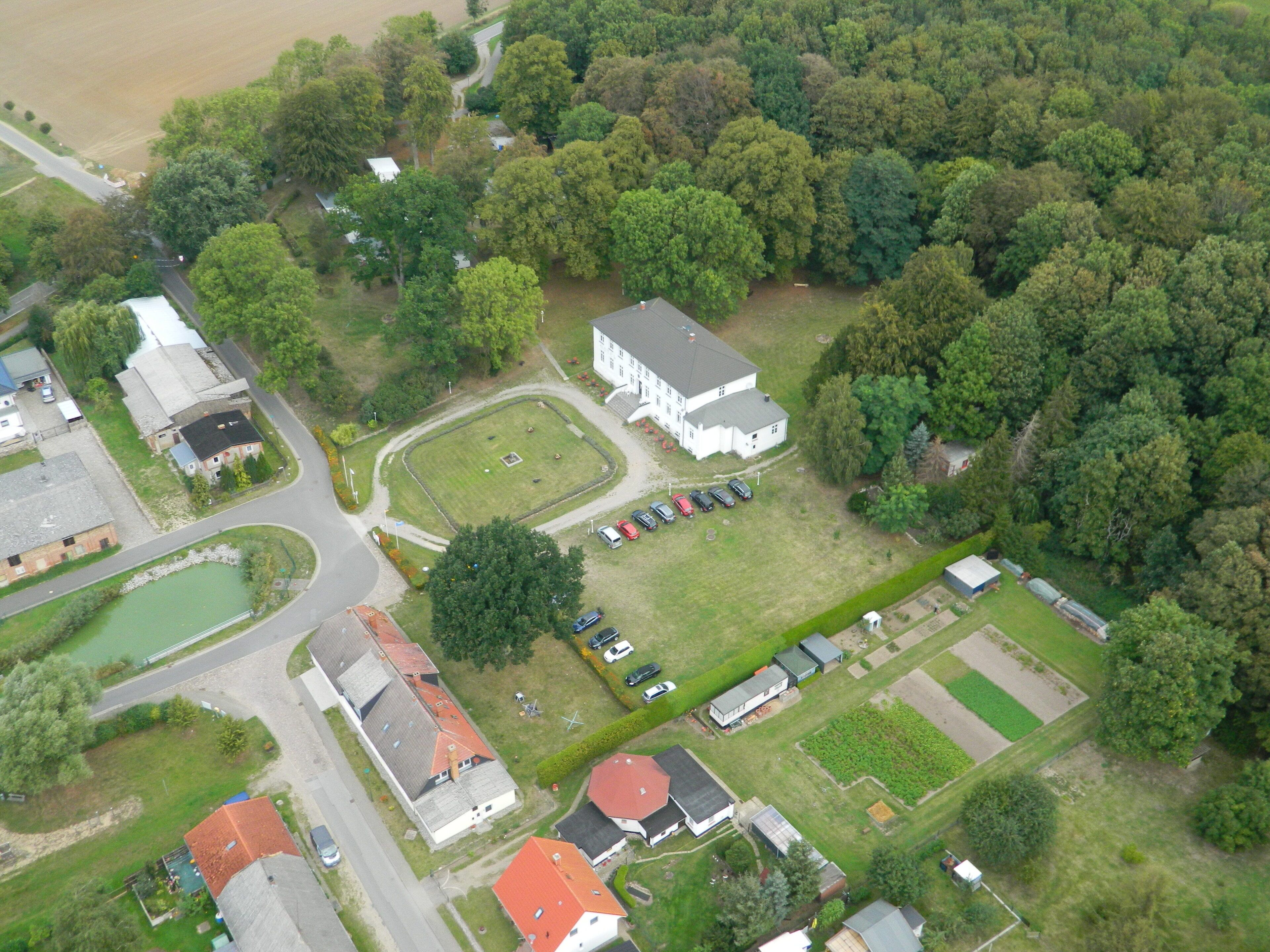 An aerial view of a residential area with houses, a large white building, and a parking lot.