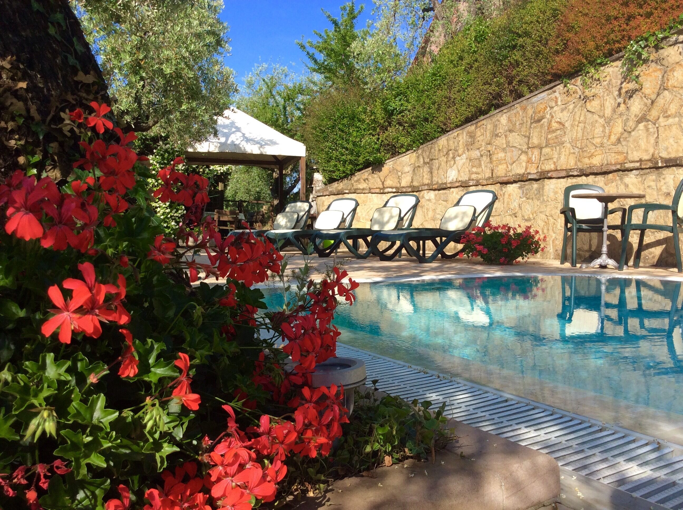 A swimming pool with lounge chairs and a stone wall.