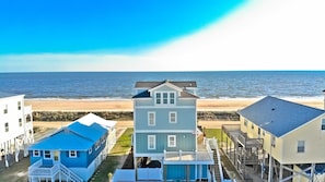 Une propriété située en bord de mer, comprenant plusieurs maisons, dont une maison principale dotée d’un toit à pignon et une plus petite maison bleue avec un toit bleu.