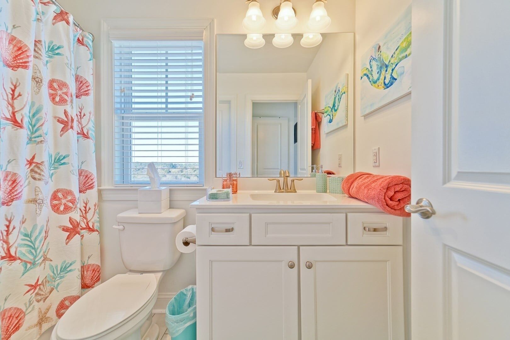 A bathroom with a toilet, sink, and shower curtain with a floral pattern.