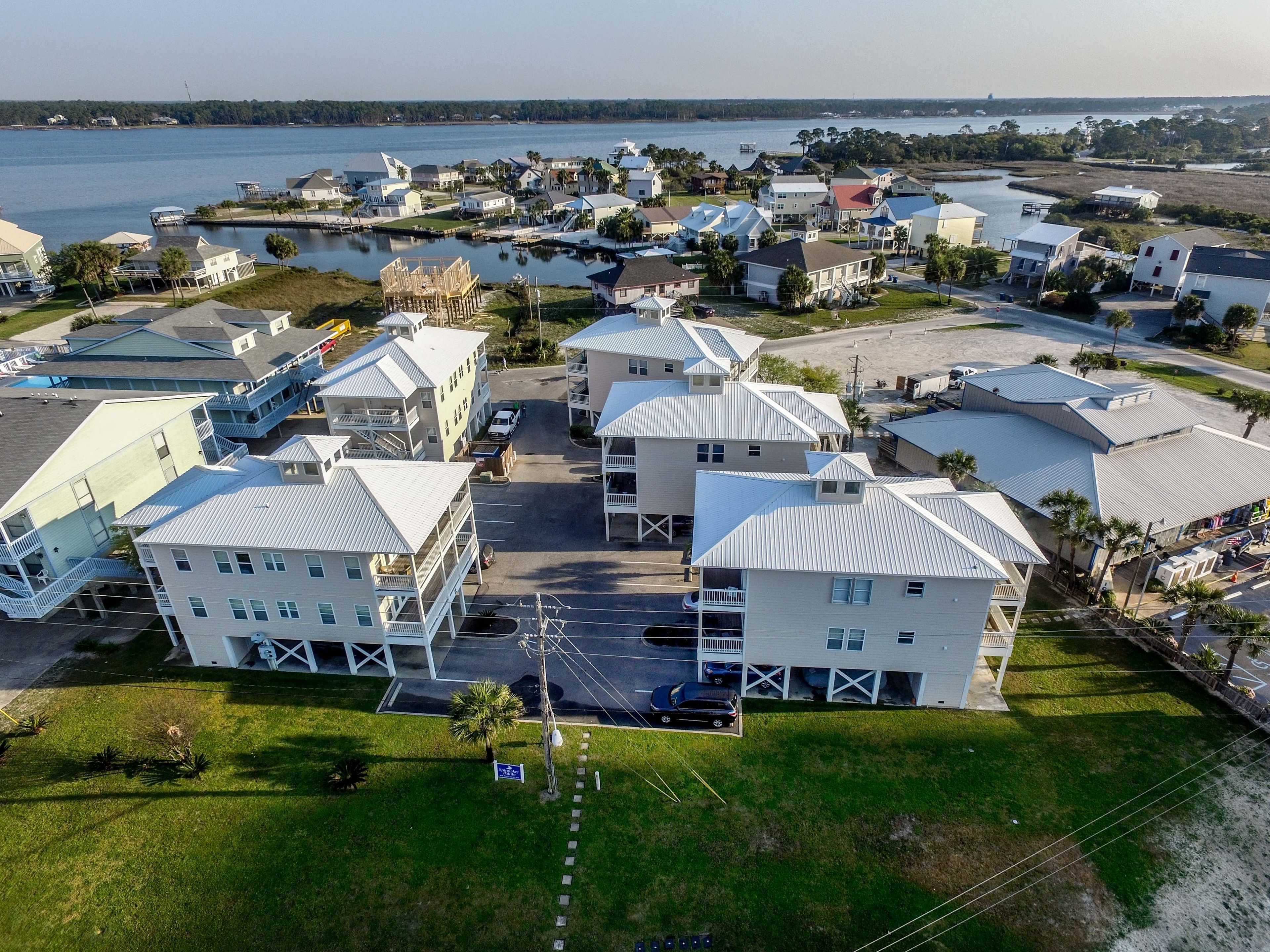 A coastal residential area with multiple two-story houses featuring gabled roofs and balconies, a marina, and a clear view of the water.