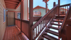 Un escalier en bois menant à un balcon d’où l’on peut admirer une maison.