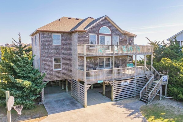 A two-story wooden house with a balcony, a basketball hoop, and a sign indicating a sand fiddler.