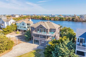 A two-story house with a balcony, located near a body of water.