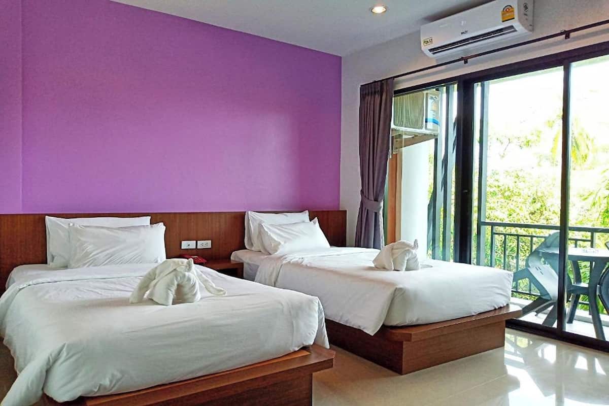 Habitación de hotel con dos camas, paredes moradas y un balcón con mobiliario exterior.