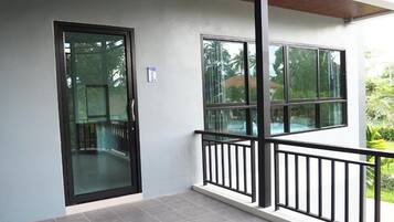 A modern building with a glass door and windows, a balcony with a black railing, and a tiled floor.