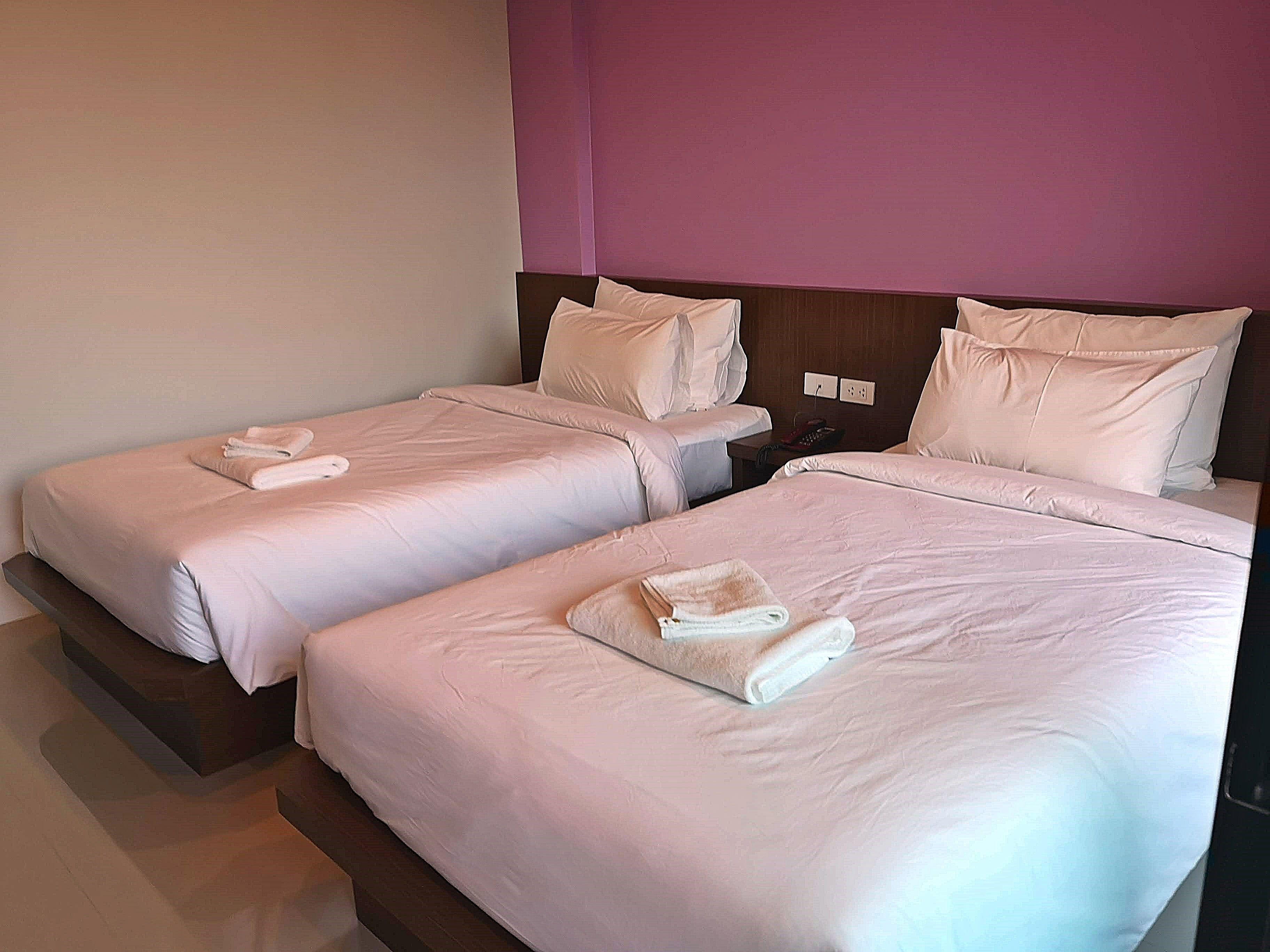 Une chambre d’hôtel avec deux lits simples, chacun muni d’un oreiller et d’une serviette pliée.