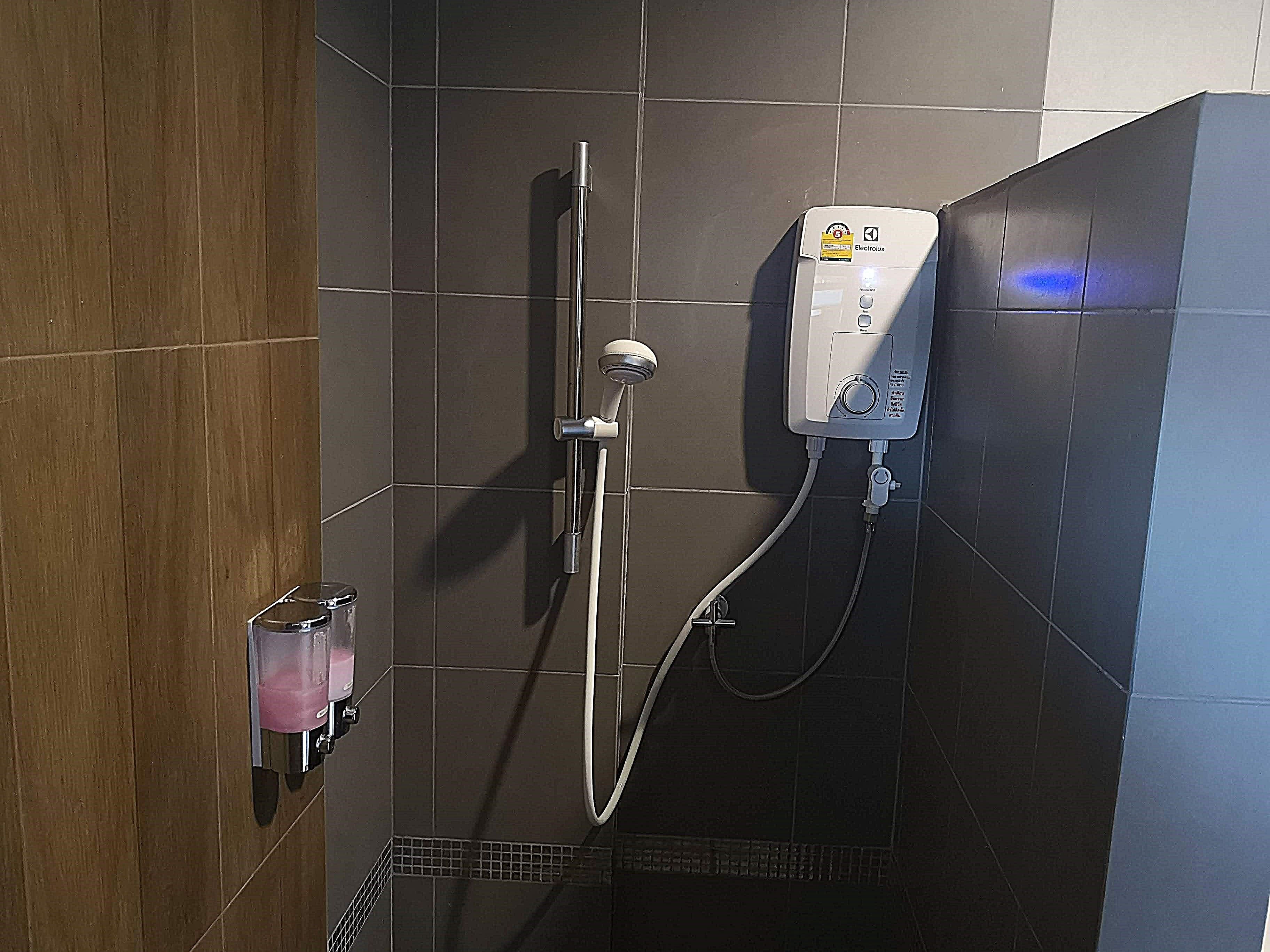 A shower with a handheld showerhead and a wall-mounted control panel.