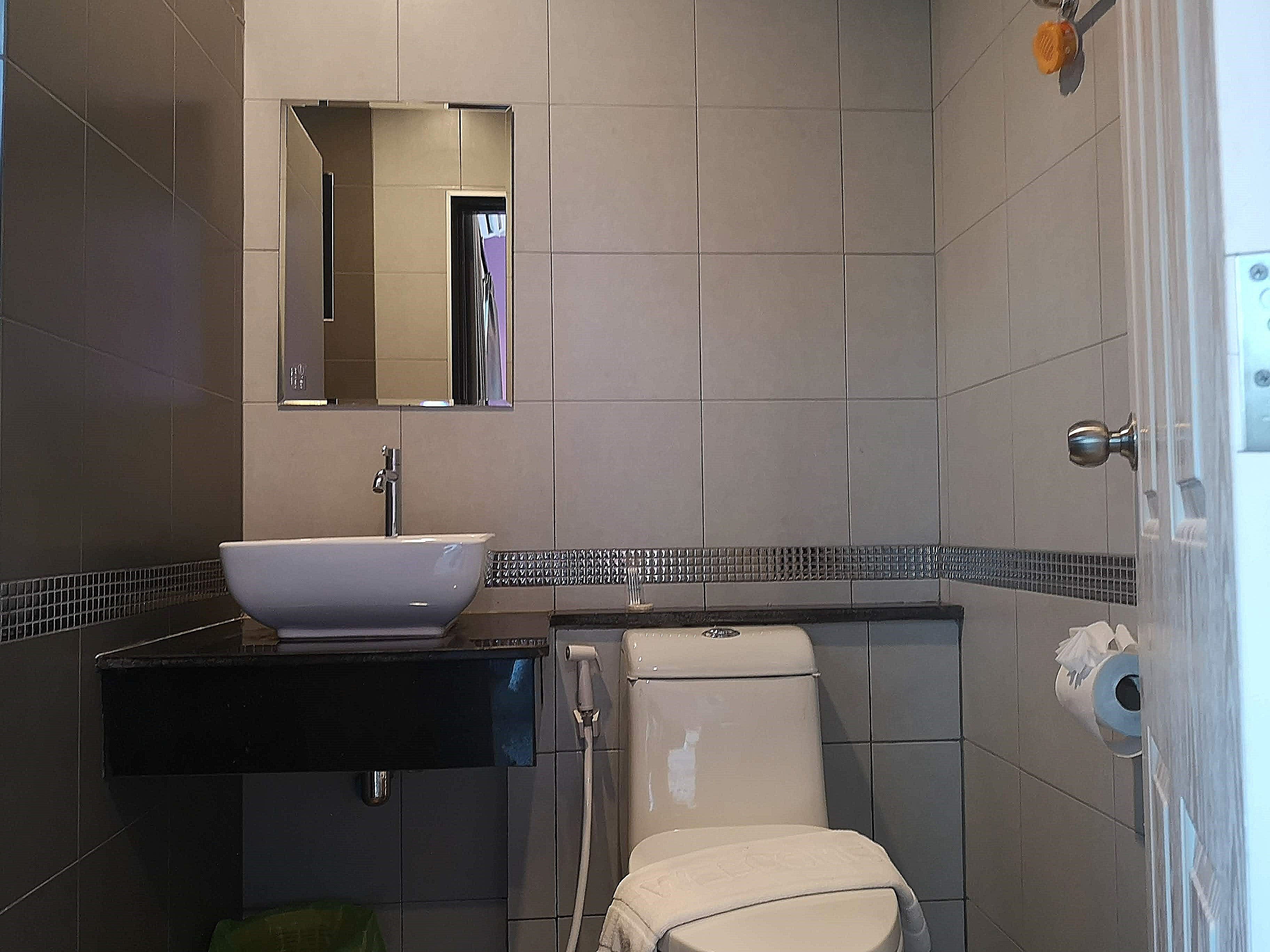 Een badkamer met een witte wastafel, een spiegel, een toilet en een handdoekhouder.