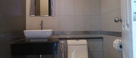 Un baño con lavamanos blanco, un espejo, inodoro y toallero.
