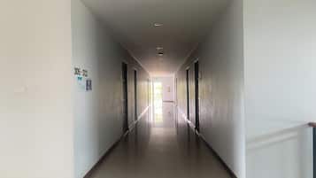 A long, narrow hallway with a series of doors on both sides, leading to a bright exit at the end.