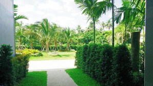 Caminho que leva a um jardim exuberante, com palmeiras e vegetação bem cuidada.