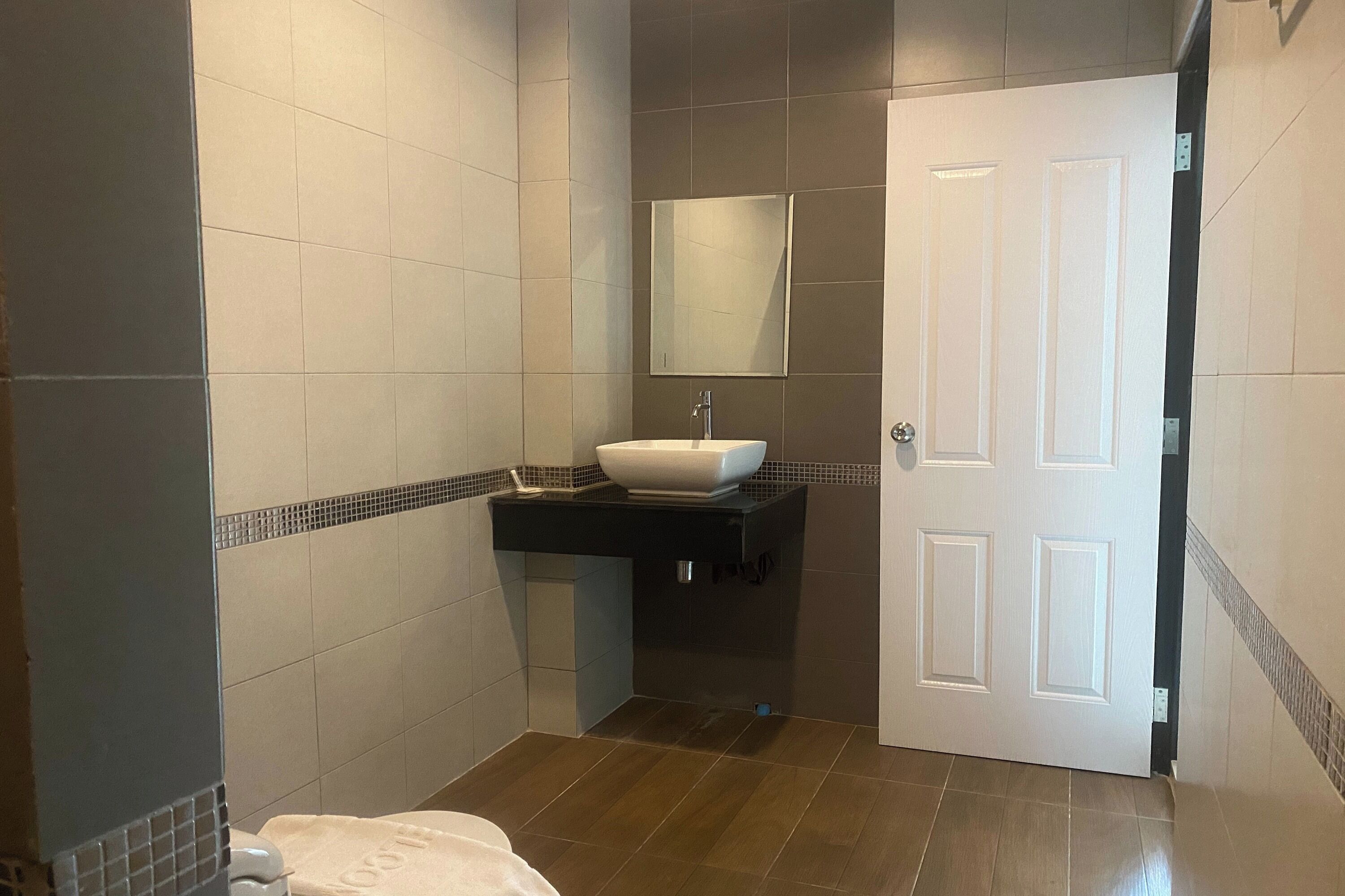Un baño con un lavabo blanco, un espejo encima y una puerta a la derecha.