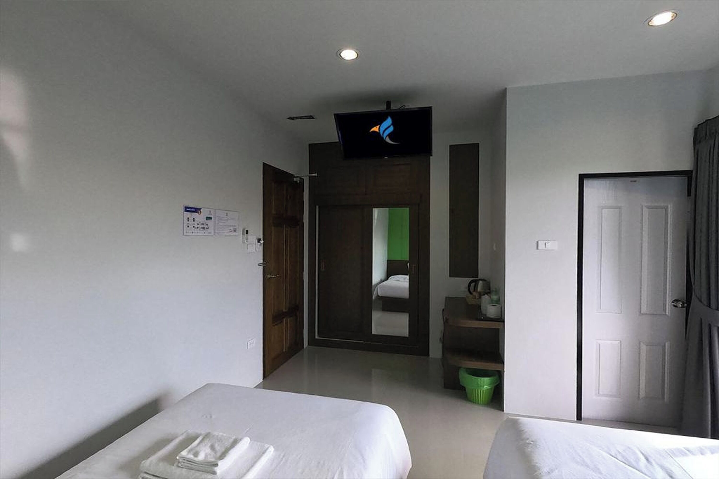 A hotel room with two beds, a television, a door, and a mirror.